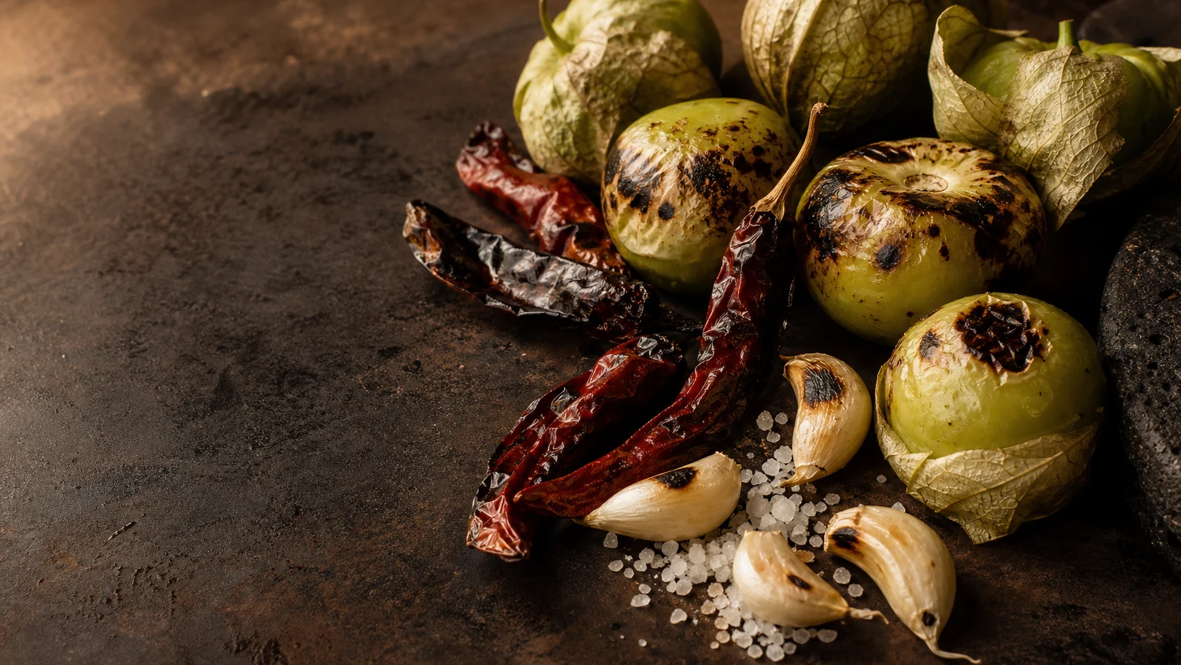 Tomatillos, chiles de árbol, ajo y sal sobre comal tatemado